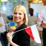 Młoda dziewczyna z flagą Polski w towarzystwie grupy osób